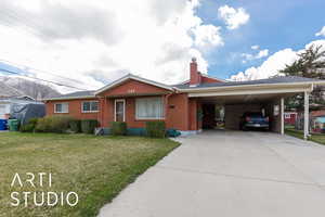Ranch-style house with a chimney, driveway, a front lawn, an attached carport, and brick siding