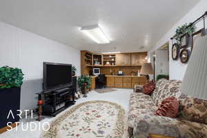Living room with built in desk, light carpet, and a textured ceiling