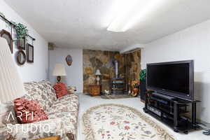 Carpeted living area featuring a wood stove and a textured ceiling