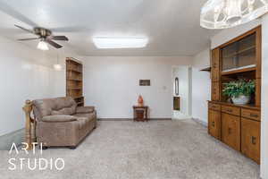 Sitting room featuring visible vents, baseboards, ceiling fan, a textured ceiling, and light carpet