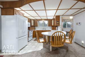 Kitchen with a sink, light countertops, white appliances, a peninsula, and brown cabinets
