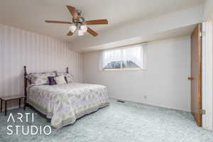 Carpeted bedroom with wallpapered walls, baseboards, and a ceiling fan