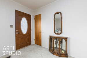 Entryway with carpet flooring and ornamental molding
