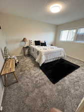 Carpeted bedroom featuring baseboards and a textured ceiling
