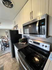 Kitchen featuring light tile patterned floors, white cabinets, and appliances with stainless steel finishes