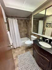 Bathroom with shower / bath combo, toilet, tile patterned flooring, and vanity