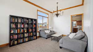 Carpeted living room with crown molding, baseboards, a healthy amount of sunlight, and a chandelier