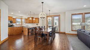 Dining room with dark wood-type flooring, baseboards, a notable chandelier, and recessed lighting