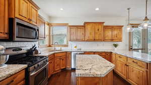 Kitchen with brown cabinets, a sink, a kitchen island, a peninsula, and appliances with stainless steel finishes