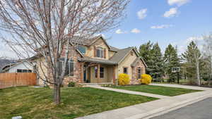 View of front of house featuring stucco siding, fence, stone siding, and a front yard
