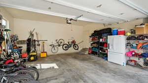 Garage featuring white refrigerator with ice dispenser and a garage door opener