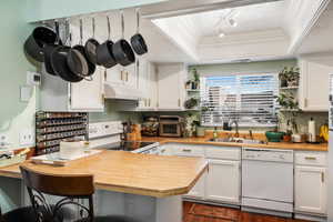 Kitchen with white appliances, a peninsula, open shelves, under cabinet range hood, and a sink