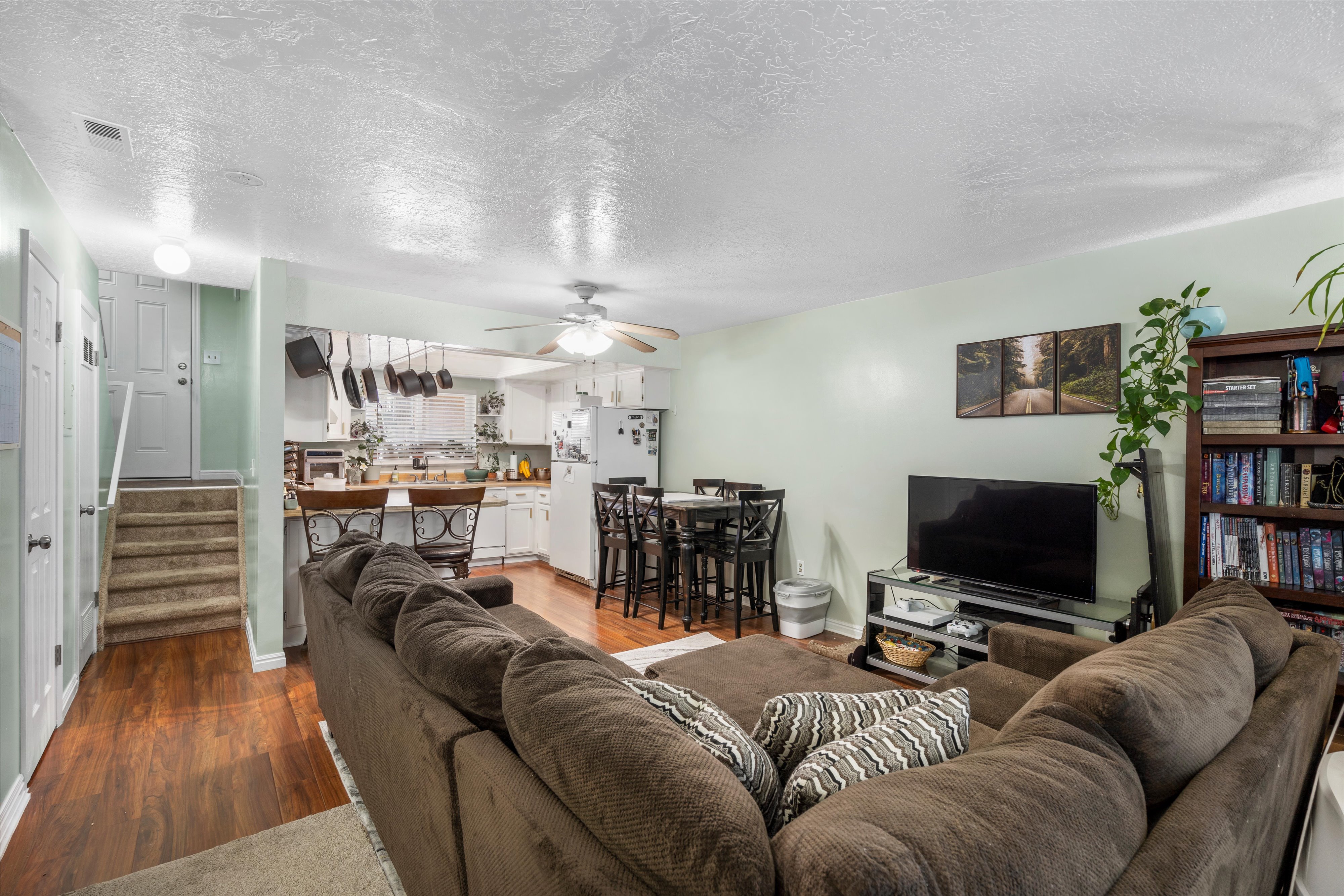 Living room featuring a ceiling fan, stairs, wood finished floors, and a textured ceiling