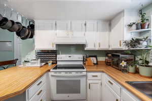 Kitchen featuring a textured ceiling, white cabinetry, ventilation hood, white range with electric stovetop, and a sink