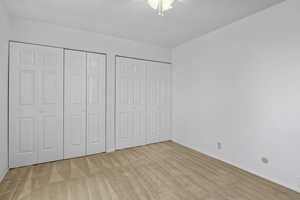 Unfurnished bedroom featuring baseboards, ceiling fan, carpet, and two closets