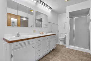 Full bath with a sink, a stall shower, toilet, and double vanity