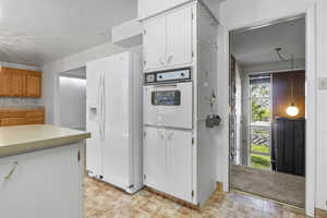 Kitchen featuring white appliances, white cabinets, and light countertops