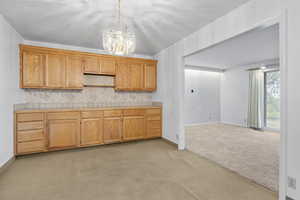Kitchen with backsplash, pendant lighting, open shelves, an inviting chandelier, and light carpet
