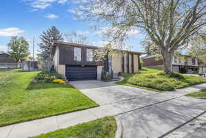 View of front of home with a garage, fence, a front yard, brick siding, and driveway