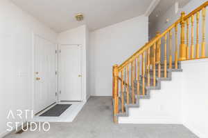 Entryway with lofted ceiling, tile patterned floors, carpet flooring, and stairs