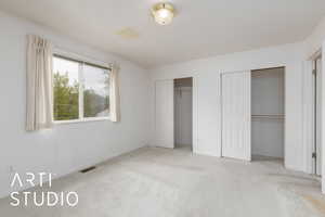 Unfurnished bedroom featuring baseboards, two closets, visible vents, and carpet floors