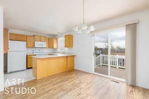 Kitchen featuring light countertops, visible vents, white appliances, a peninsula, and a chandelier