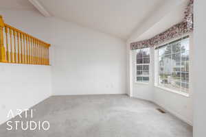 Carpeted spare room with vaulted ceiling, visible vents, and baseboards
