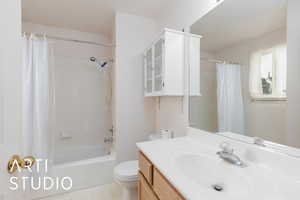 Bathroom with toilet, vanity, and shower / tub combo with curtain