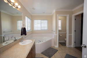 Principle Bathroom with dual sinks, crown molding, a garden tub, separtate shower, tile patterned flooring, and toilet