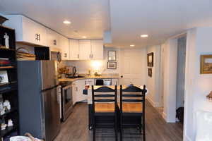 Kitchen featuring dark wood-type flooring, appliances with stainless steel finishes, white cabinetry, and a sink