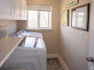 Clothes washing area with baseboards, washer and clothes dryer, and cabinet space
