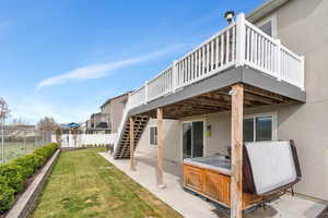 Back of property with stucco siding, a wooden deck, a hot tub, and a fenced backyard