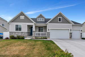 Craftsman-style home with a front lawn, concrete driveway, an attached garage, stone siding, and a porch