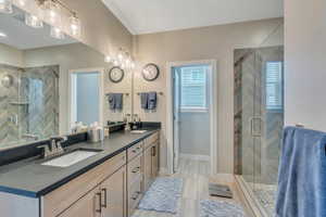 Bathroom featuring baseboards, plenty of natural light, a stall shower, and a sink