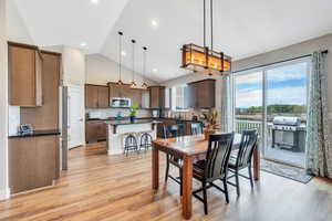 Dining room with light wood finished floors, a toaster, high vaulted ceiling, and recessed lighting