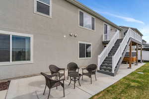 Back of house with stucco siding, stairway, and a patio