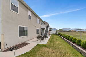 Back of property featuring a fenced backyard, a mountain view, a lawn, stairway, and stucco siding