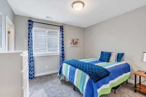 Carpeted bedroom featuring visible vents and baseboards
