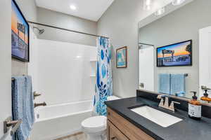 Full bathroom featuring toilet, vanity, and shower / bathtub combination with curtain