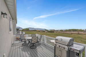 Wooden terrace with a lawn, a rural view, outdoor dining area, grilling area, and a mountain view