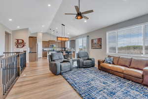 Living room with lofted ceiling, a ceiling fan, recessed lighting, and light wood-style floors