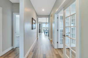Hallway with recessed lighting, wood finished floors, baseboards, and french doors