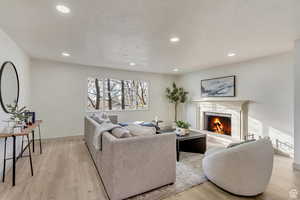 Living area with light wood-style flooring, baseboards, recessed lighting, and a high end fireplace