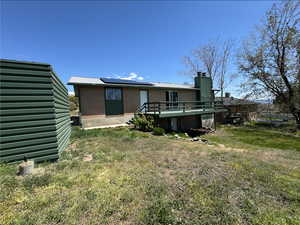 Rear view of house featuring a yard, a wooden deck, brick siding, and roof mounted solar panels