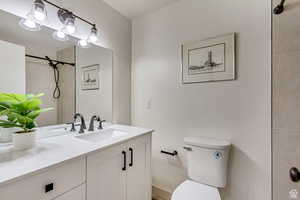 Full bathroom with a tile shower, toilet, and vanity