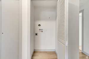 Clothes washing area featuring hookup for an electric dryer, baseboards, light wood-style floors, washer hookup, and laundry area