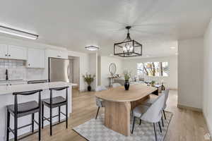 Dining room featuring light wood-style floors, baseboards, and a notable chandelier