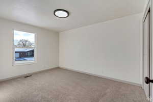 Spare room with light carpet, visible vents, and baseboards