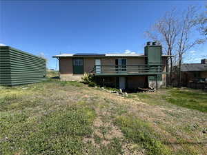 Back of house with a chimney, roof mounted solar panels, a yard, a wooden deck, and brick siding