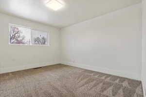 Empty room featuring baseboards, visible vents, and carpet floors
